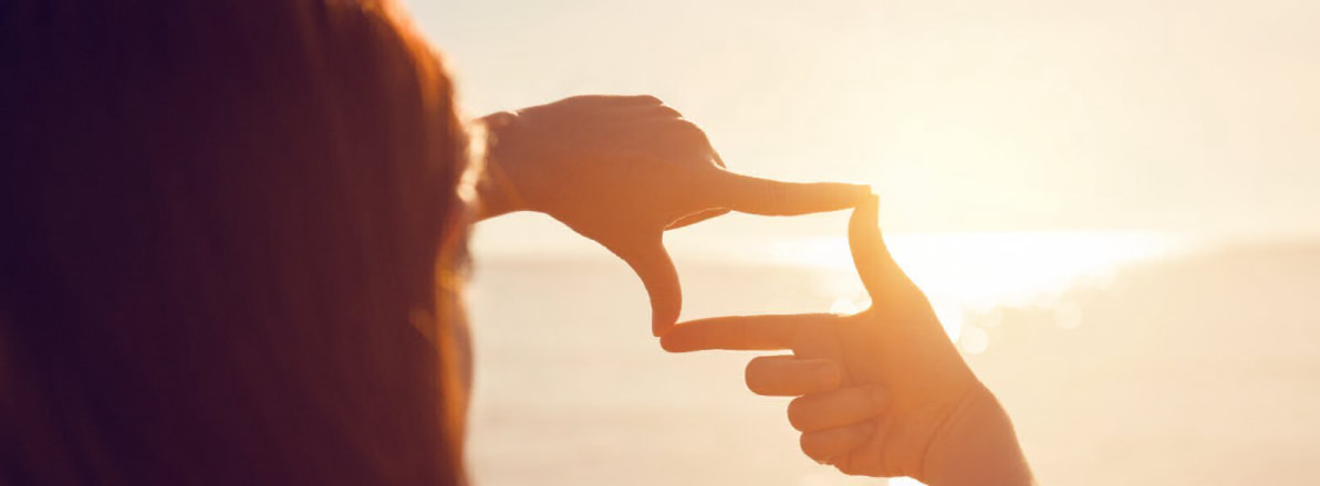 Person framing the sunrise with hands